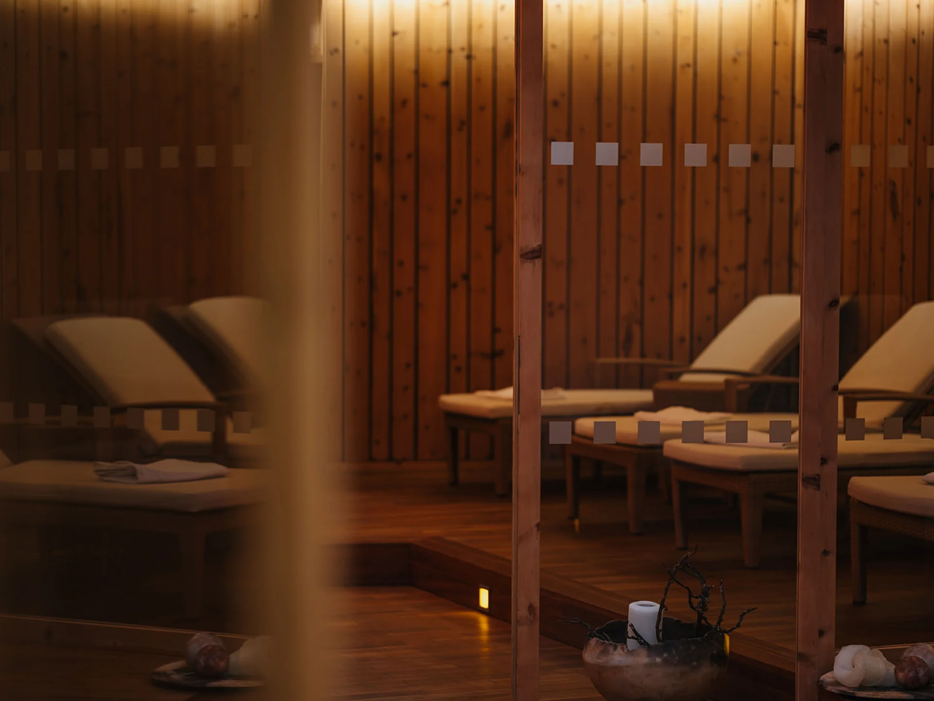 Relaxation room with lounge chairs and candle inside wooden sauna
