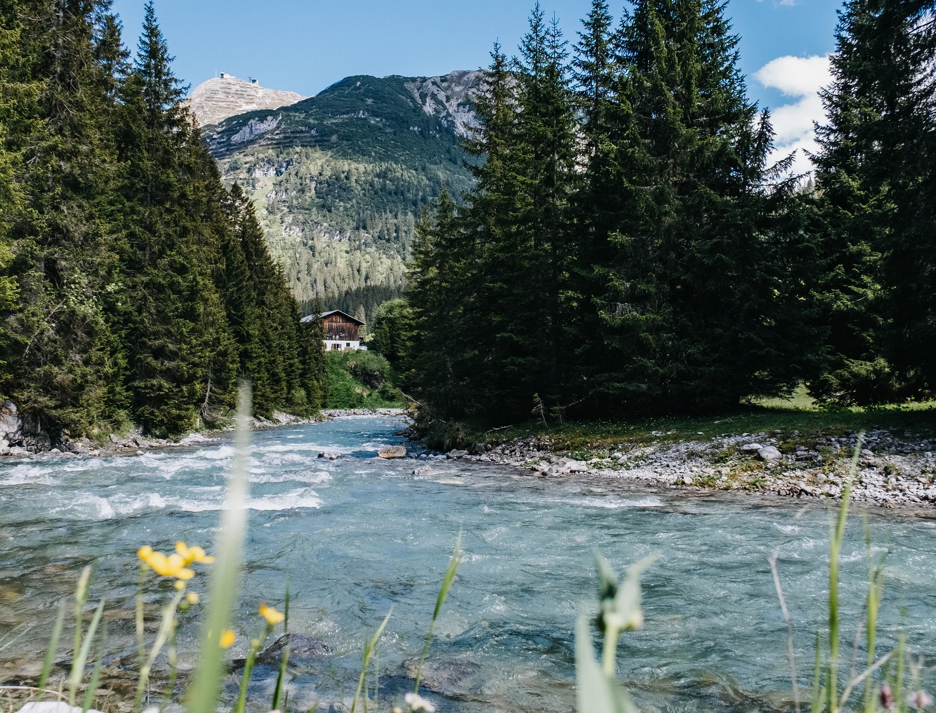 Am Lech entlang Bergfluss mit grünem Wald und Haus bei klarem blauem Himmel