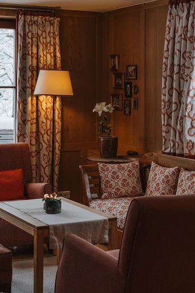 Gemütliches Wohnzimmer mit Holzwänden, Sessel und Schneeblick außen