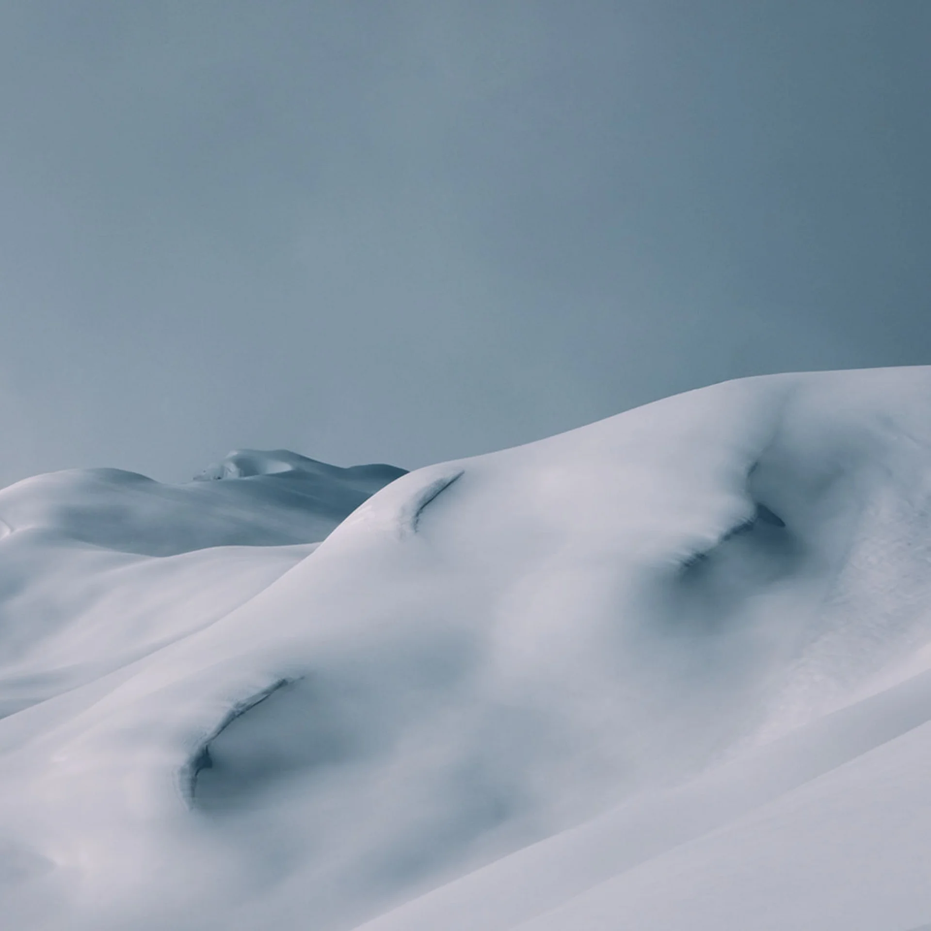 Sanfte schneebedeckte Hügel unter bewölktem Himmel