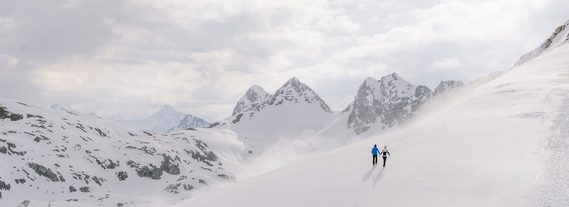 Mann und Frau machen eine Winterwanderung mit traumhaften Bergpanorama.