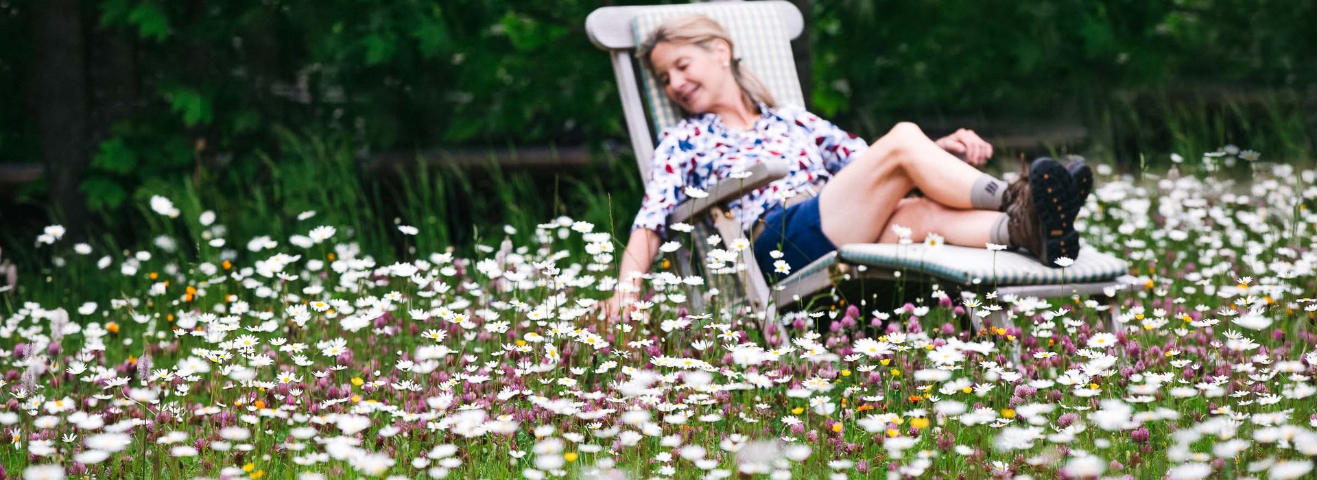 Dame liegt am Liegestuhl in einer Blumenwiese