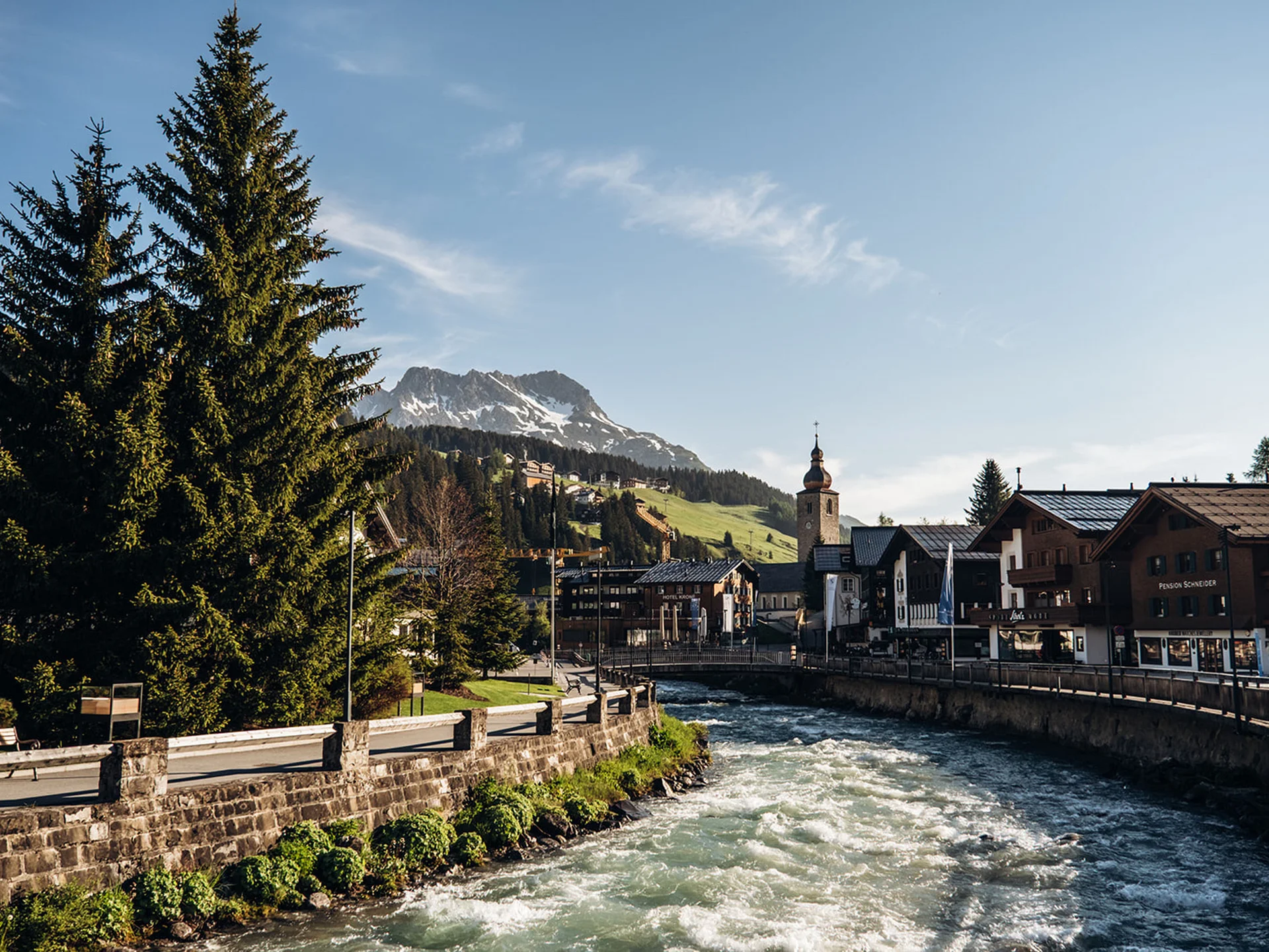 River flowing through alpine town with mountain backdrop and church tower