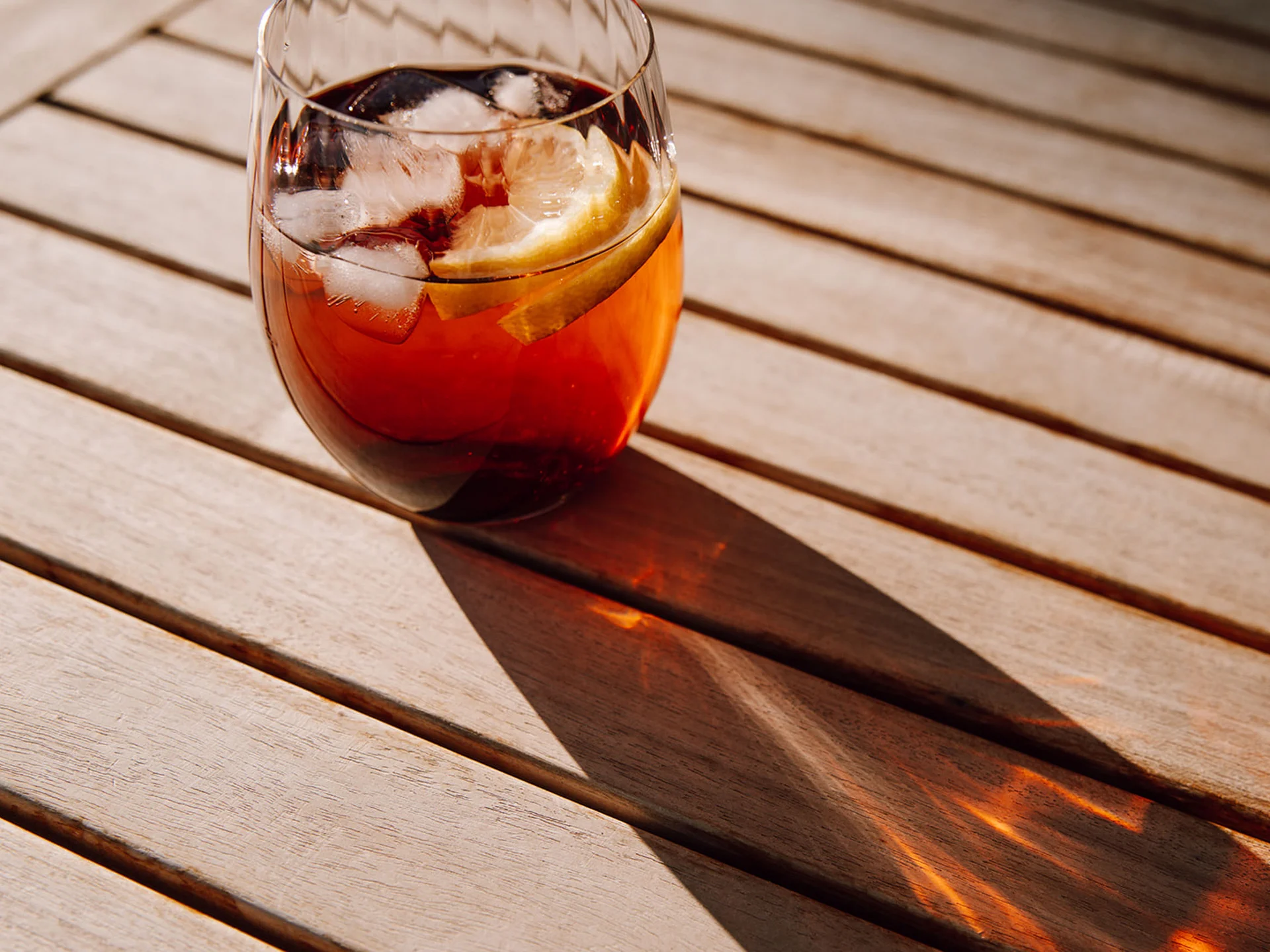 Glass of iced tea with ice and lemon slice on wooden table