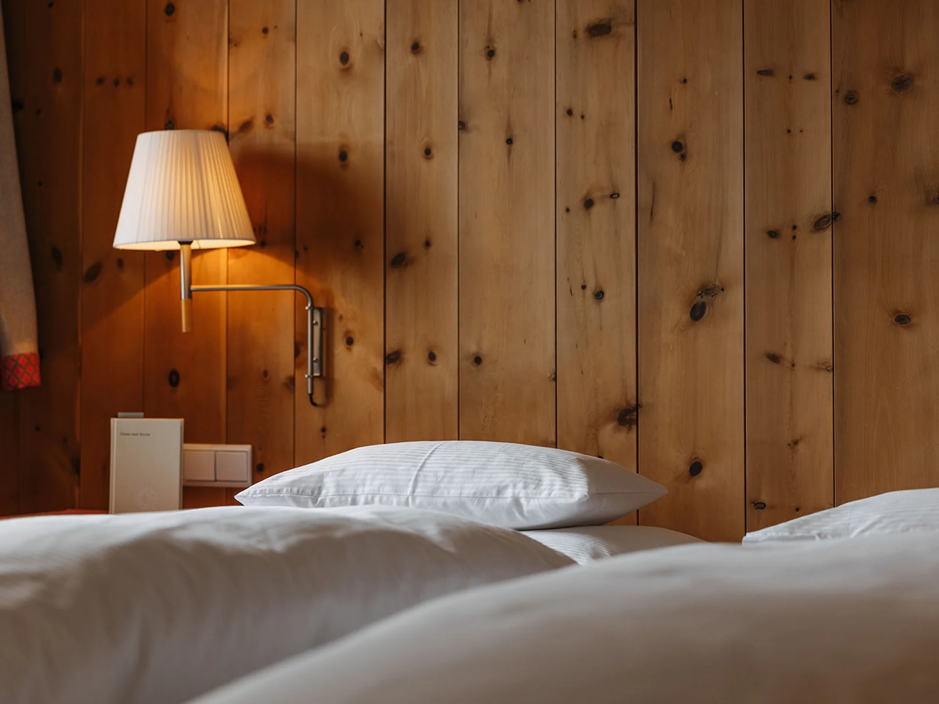 White bed with pillow and wall lamp on wooden panel wall