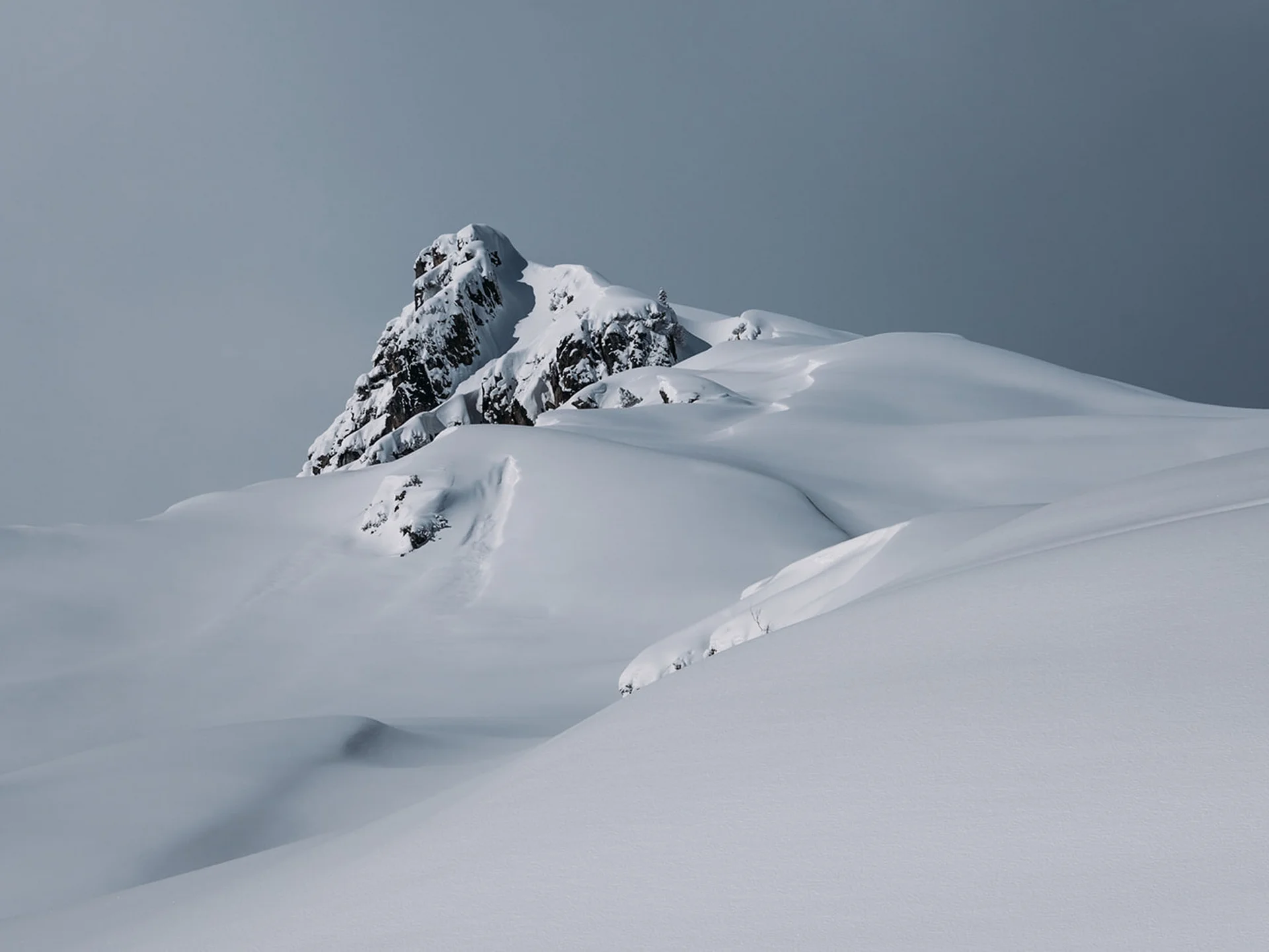 Snow-covered mountain peak under gray sky
