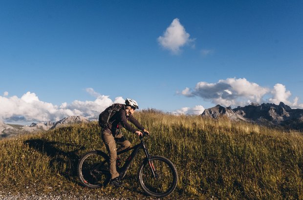 Mountainbikerin fährt über die Almwiesen.