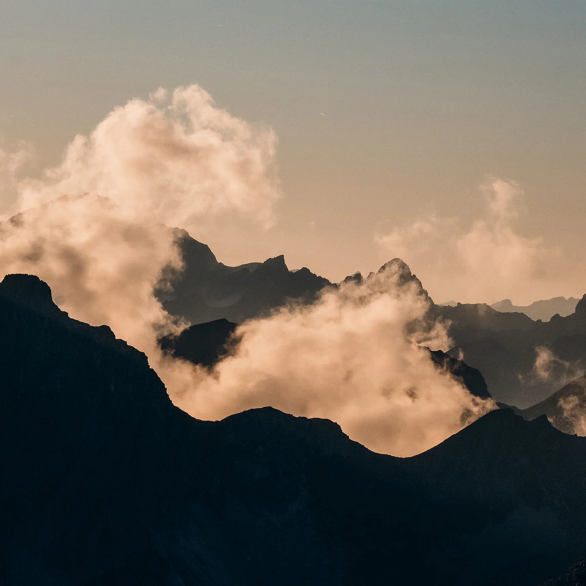 Berggipfel im Nebel bei Sonnenuntergang mit orangefarbenem Himmel