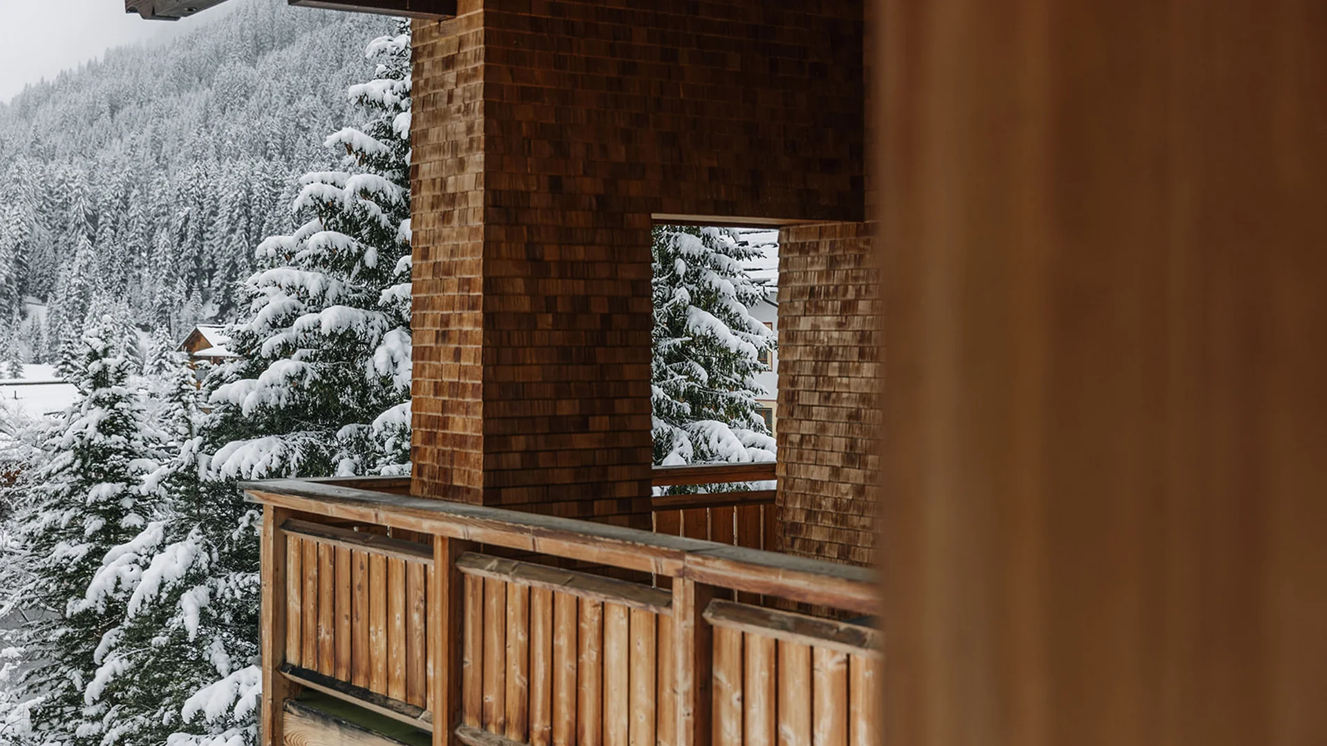 Verschneiter Wald mit Holzhaus und Balkon im Winter