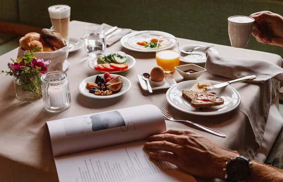 Frühstückstisch gedeckt mit frischem Obst, Brot, gekochtes Ei, Kaffee und frisch gepresstem Orangensaft.