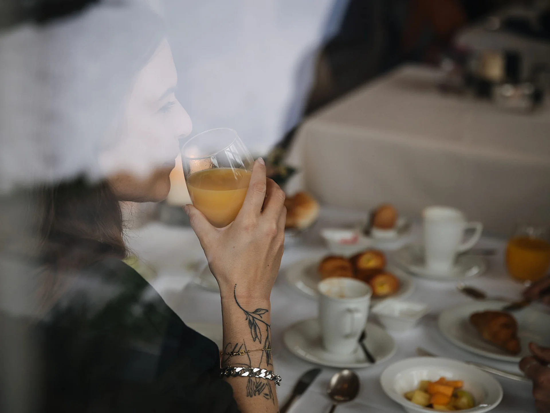 Woman drinking orange juice at a table set for breakfast