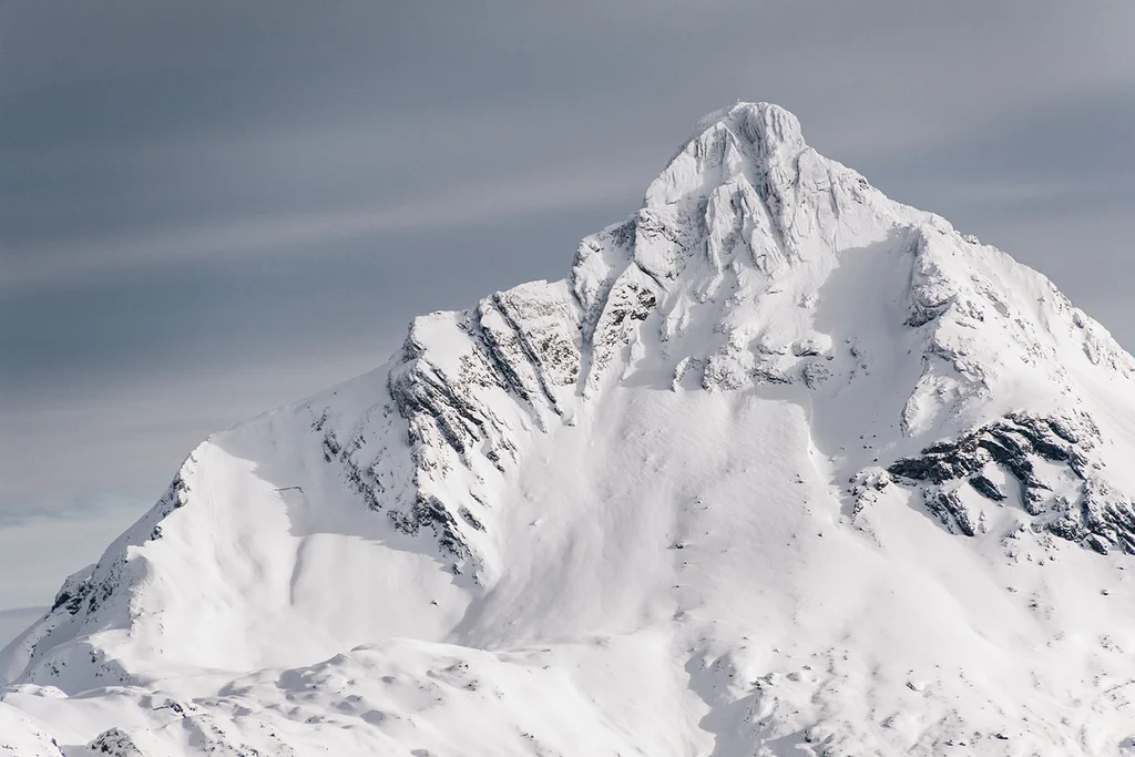 Verschneiter Berggipfel unter grauem Himmel