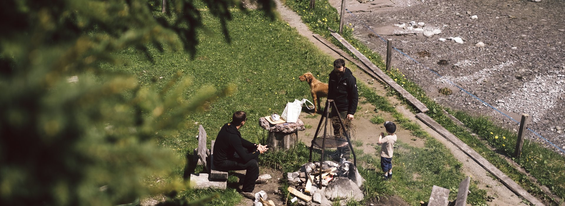 Familie mit Hund ist an einem Grillplatz in der Natur.