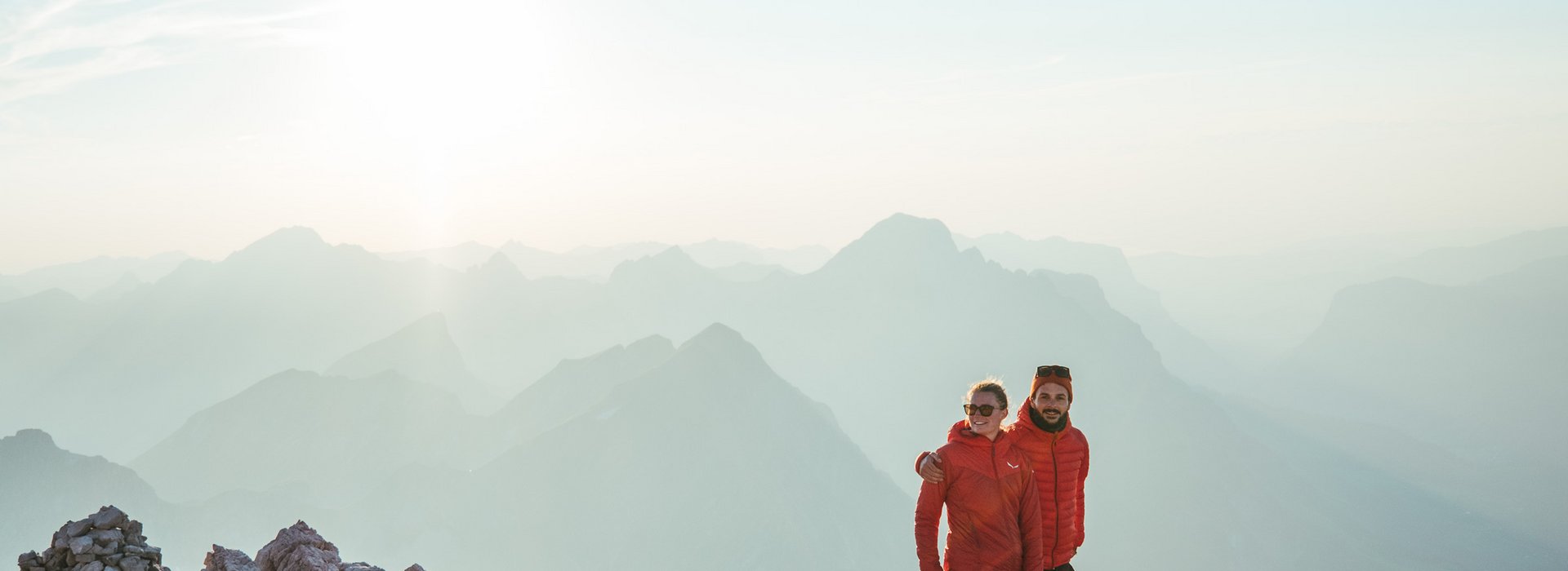 Paar steht auf schroffem Gestein mit einem Bergpanorama.