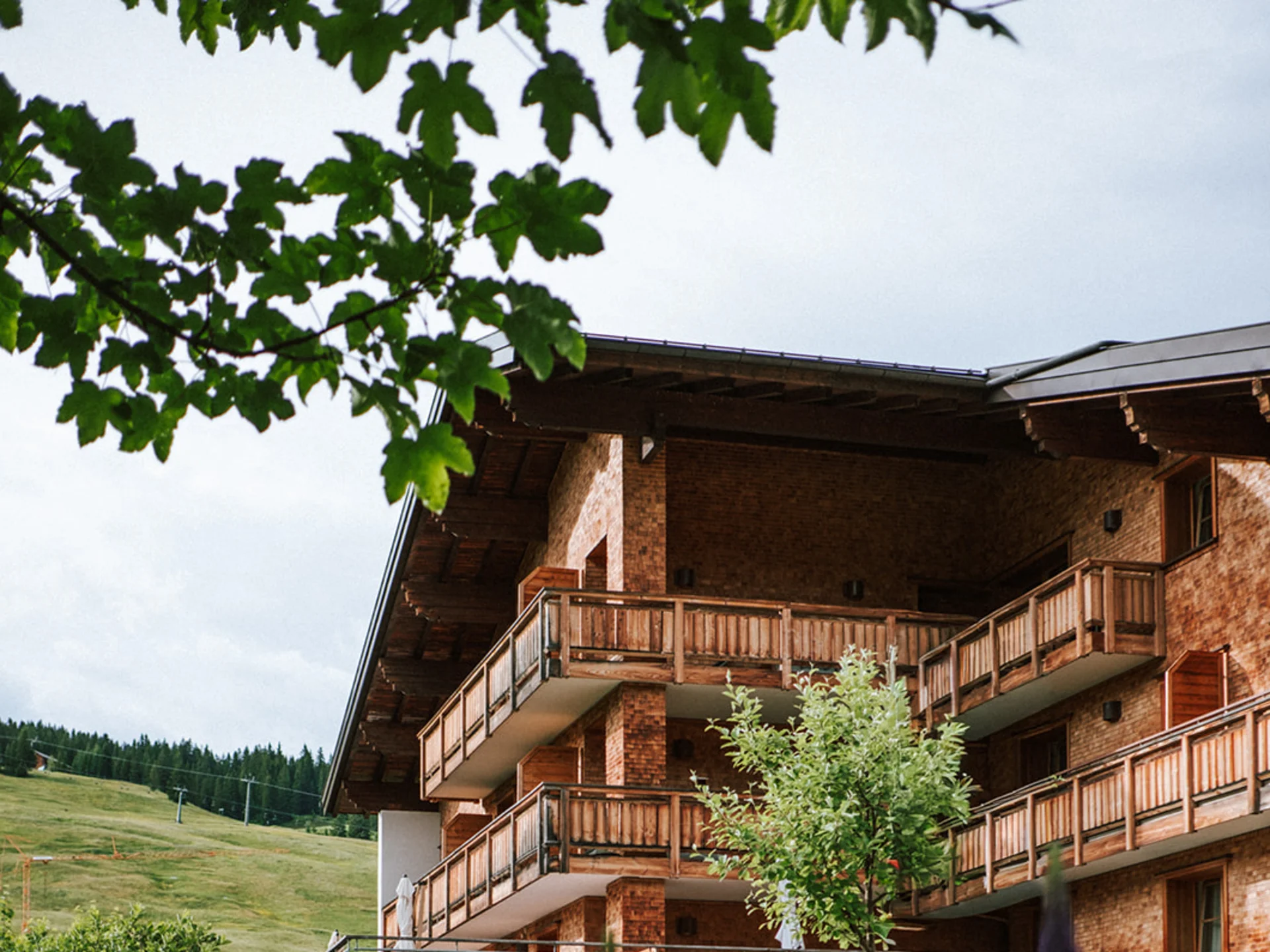 Wooden house with balconies in mountainous landscape with blooming flowers in front