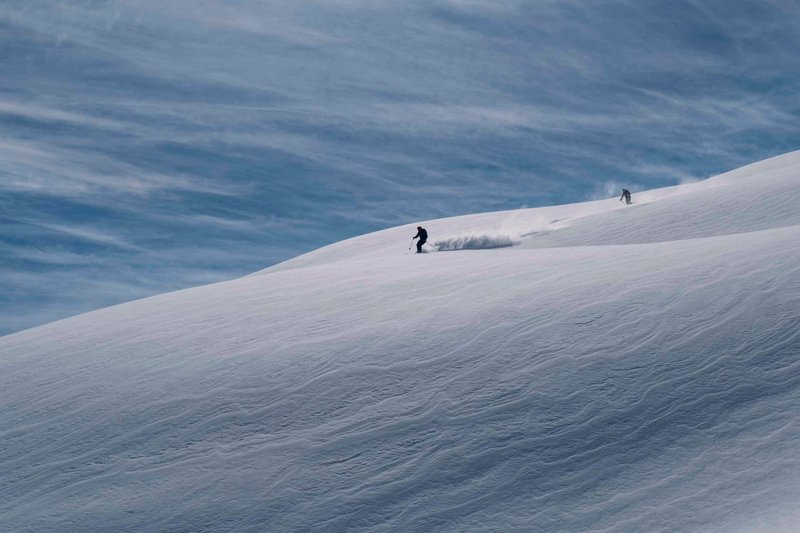 Zwei Personen fahren mit Ski durch den Tiefschnee