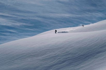 Zwei Personen fahren mit Ski durch den Tiefschnee