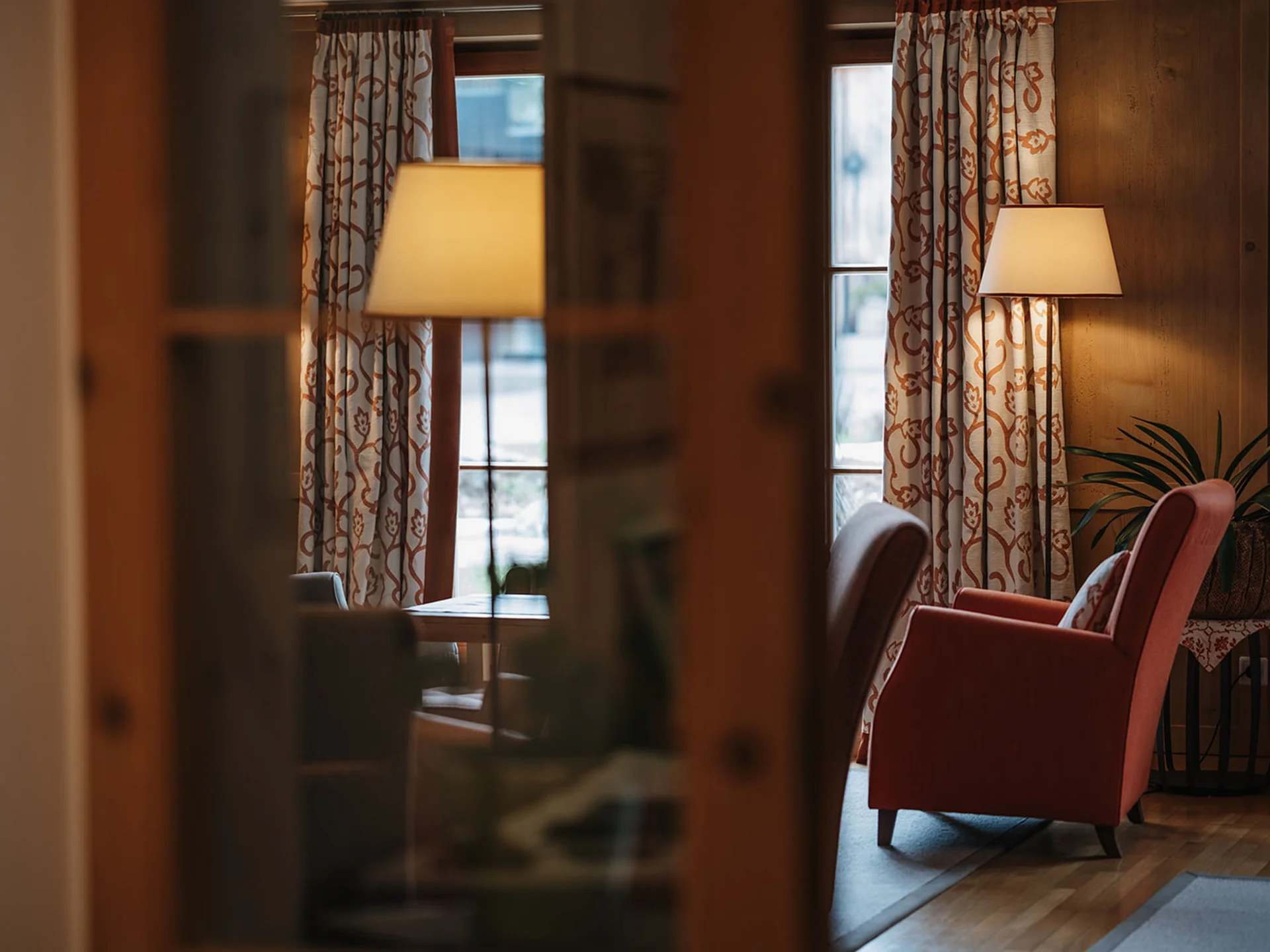 Cozy room with red armchair, lamp, and patterned curtains