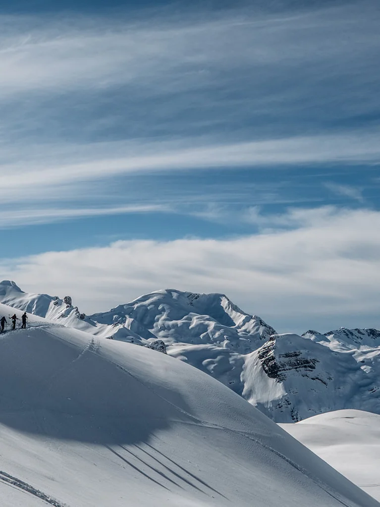 Gruppe von Wanderern auf schneebedecktem Berg mit Berggipfeln im Hintergrund