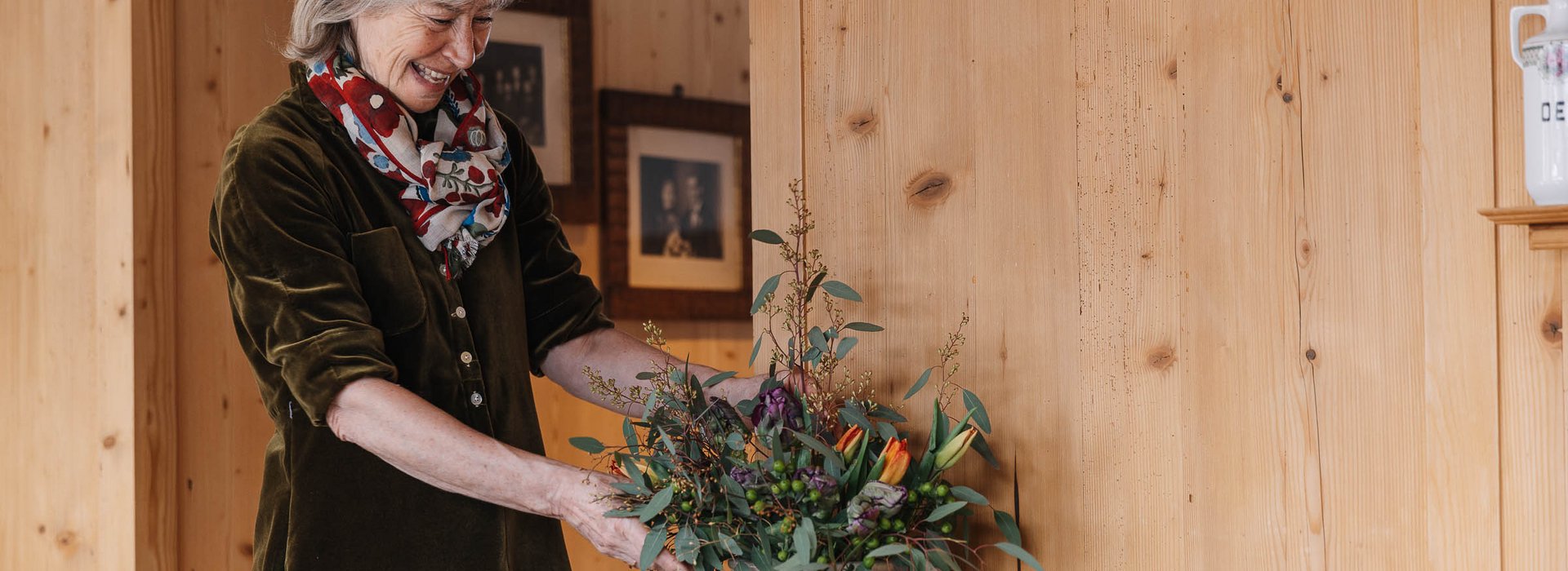 Frau stellt eine Vase mit bunten Blumen auf den Tisch.