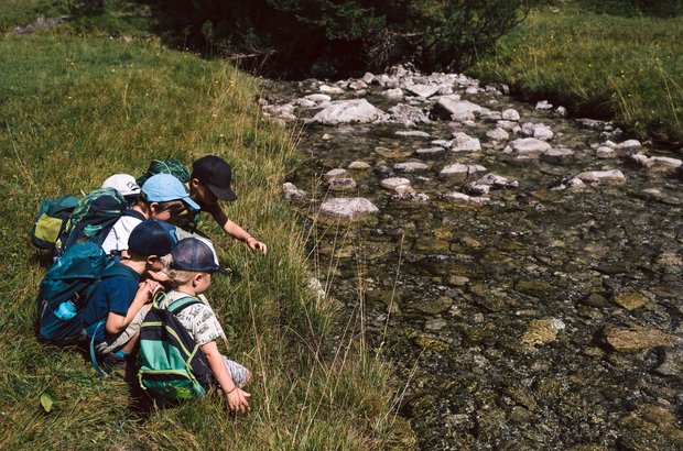 Kinder am Flussufer Kinder sitzen am Ufer des Lechs