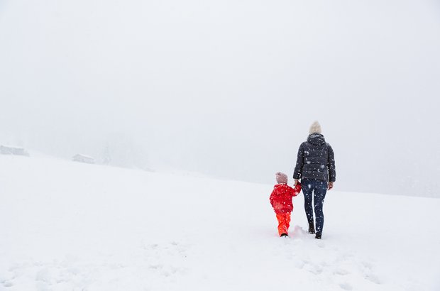 Winterwandern in Lech Frau mit Kind machen einen winterlichen Spaziergang während es schneit.