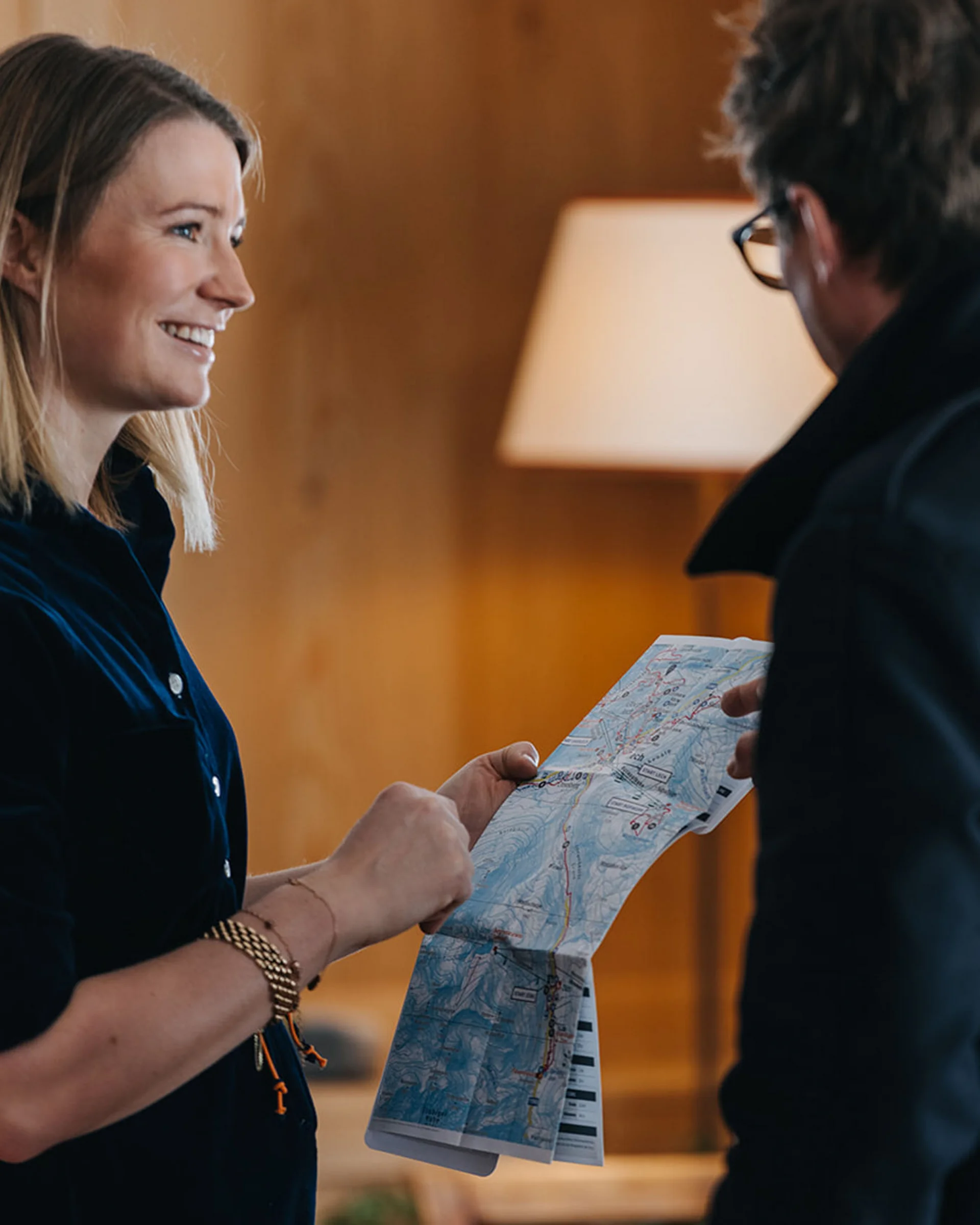 Frau und Mann sehen sich lächelnd eine Karte in einem warm beleuchteten Raum an