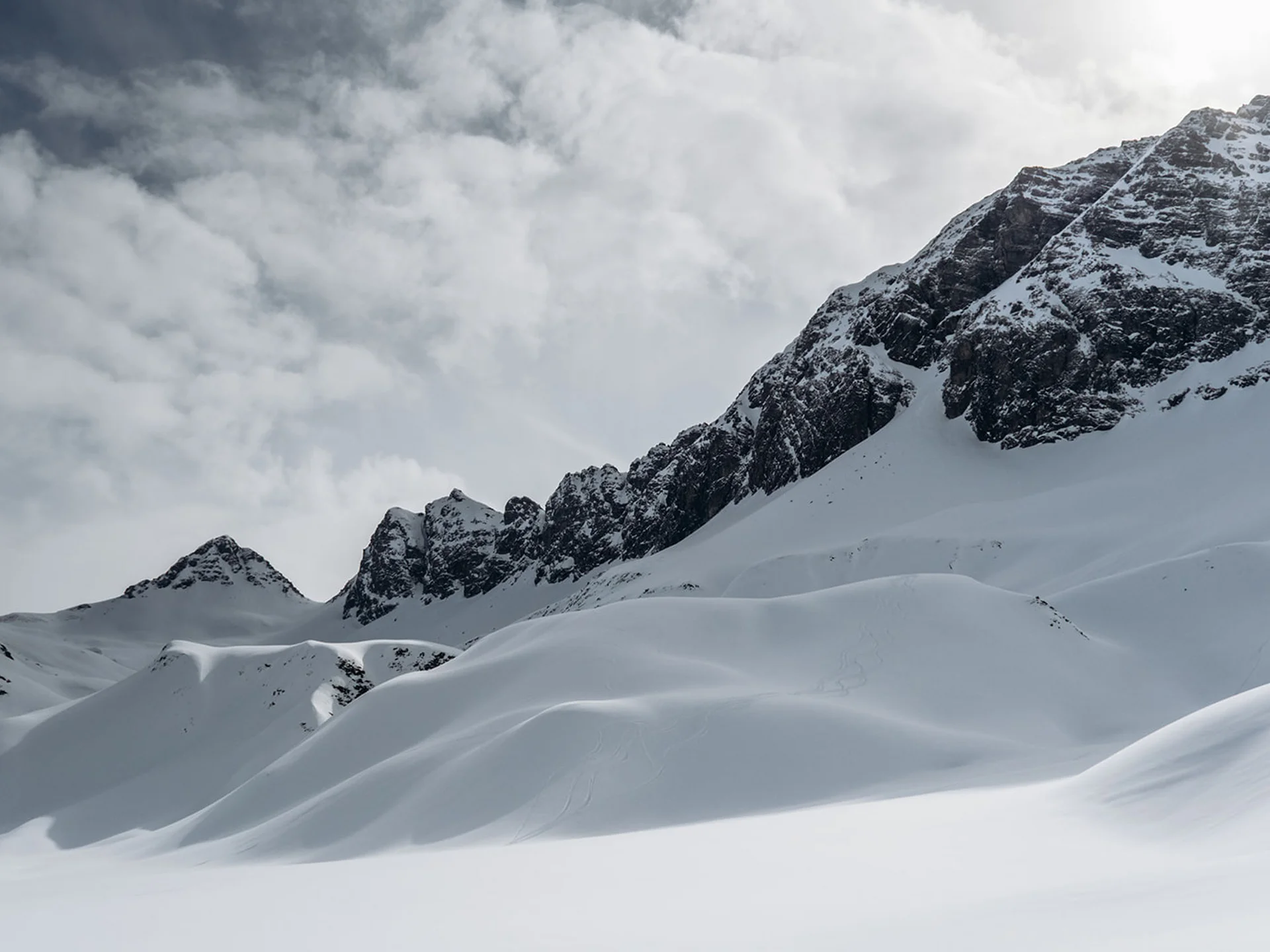 Snow-covered mountains under cloudy sky