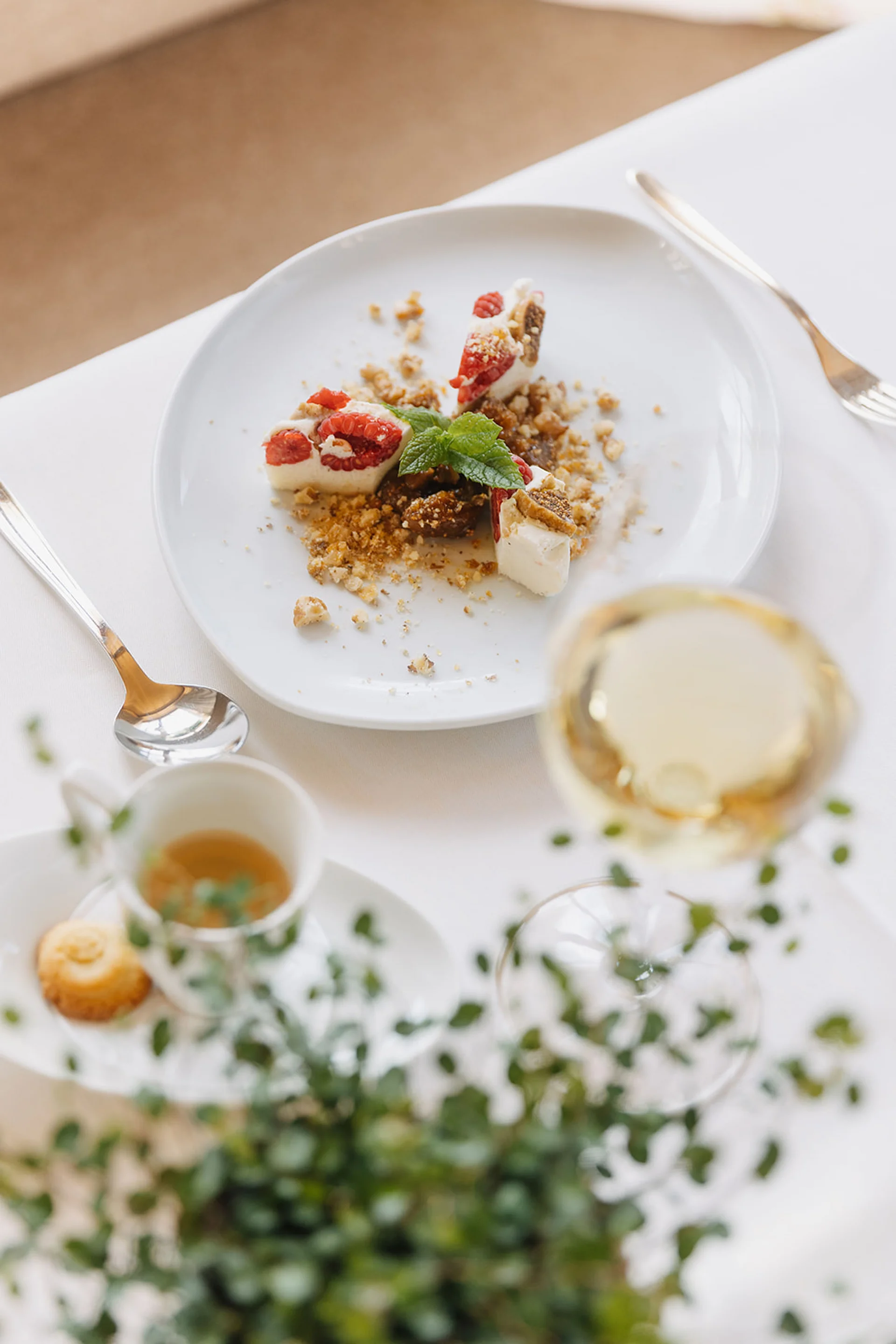 Kleiner Nachtisch mit Beeren, Keksen und Minzblatt auf weißem Teller