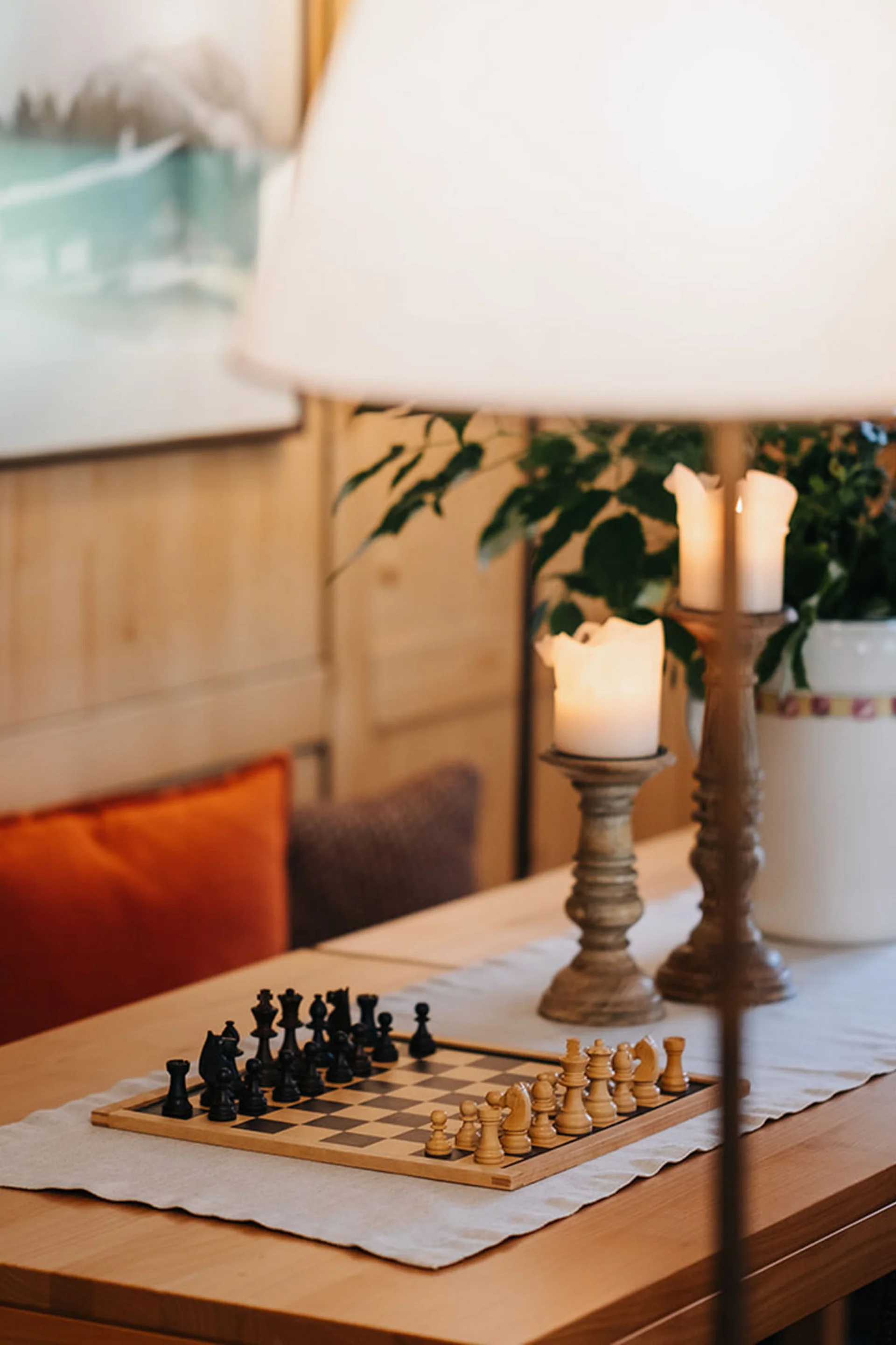 Schachbrett auf Holztisch mit Kerzen und Kissen in gemütlichem Raum