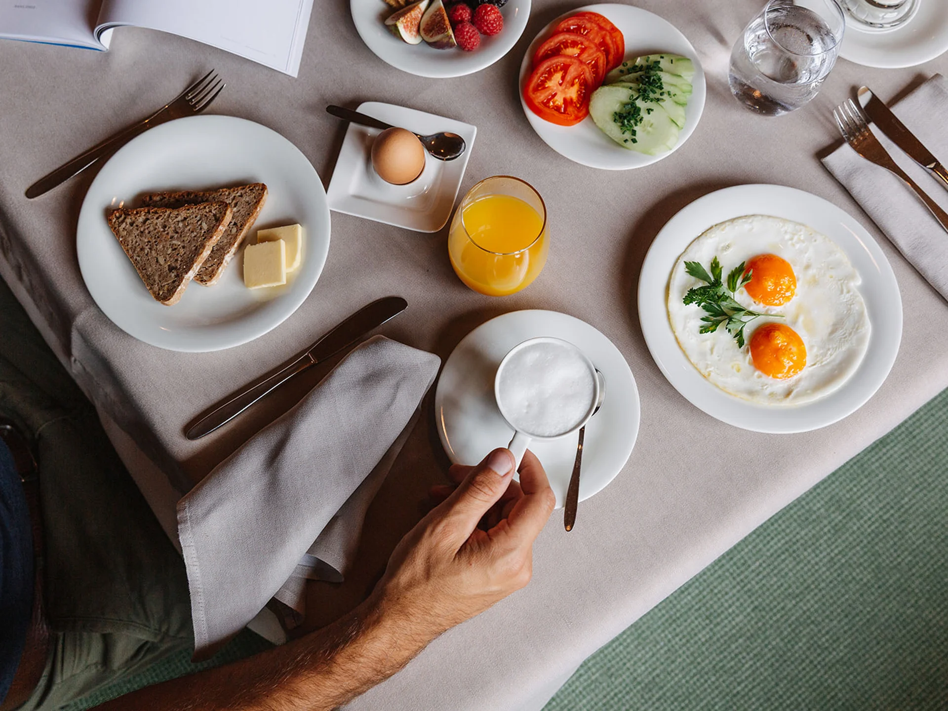 Breakfast with fried eggs, bread, butter, orange juice, coffee, and vegetables