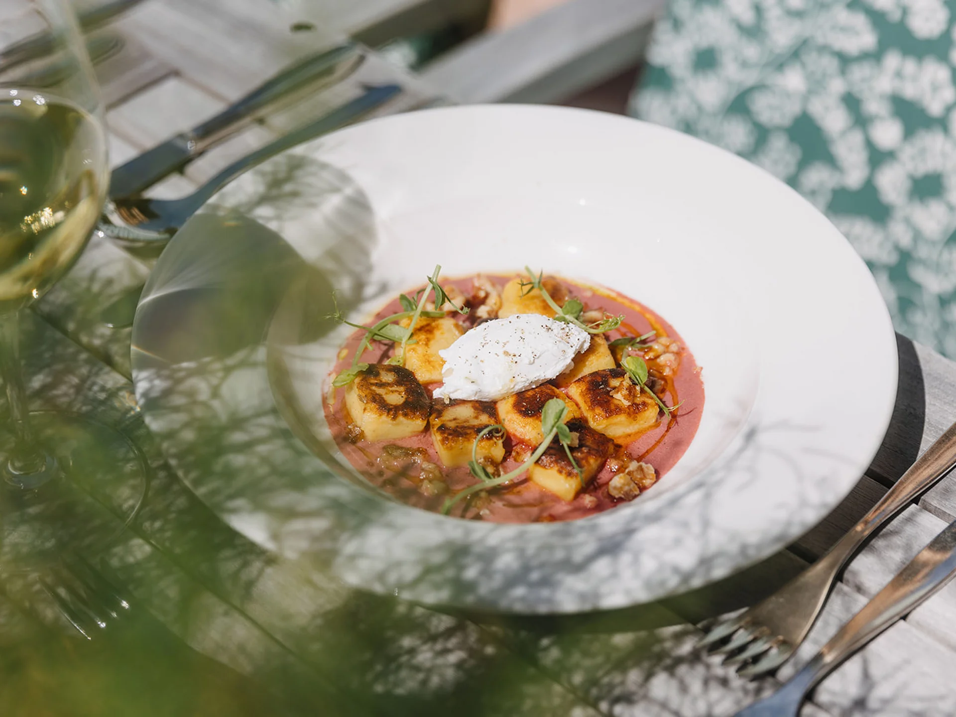 Grilled gnocchi on pink sauce garnished with herbs and cream in a white bowl