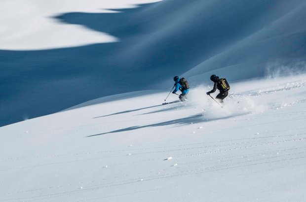 Zwei Skifahrer genießen die Abfahrt im Tiefschnee