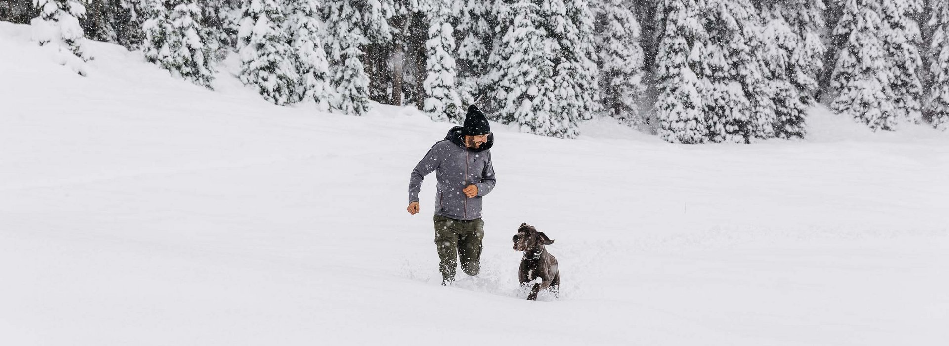 Mann spielt mit Hund im Schnee