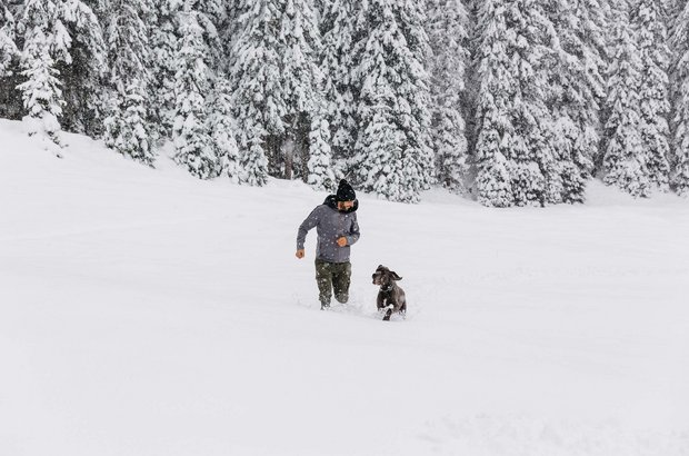Mann spielt mit Hund im Schnee