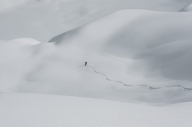 Skifahrer zieht seine Schwünge durch eine unberührte Schneelandschaft.