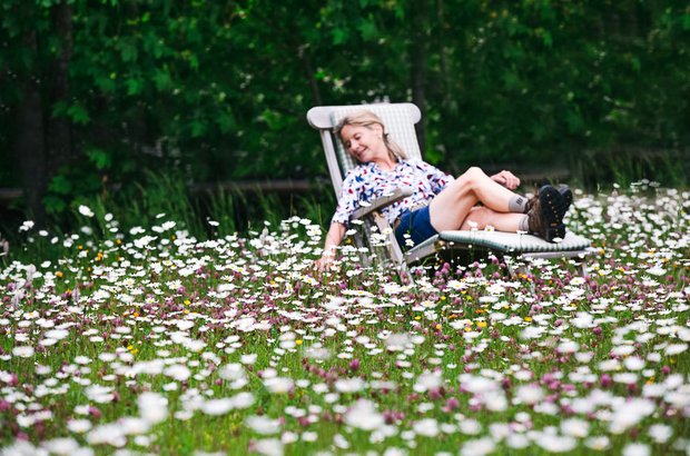 Frau auf Gartenliege in Blumenwiese