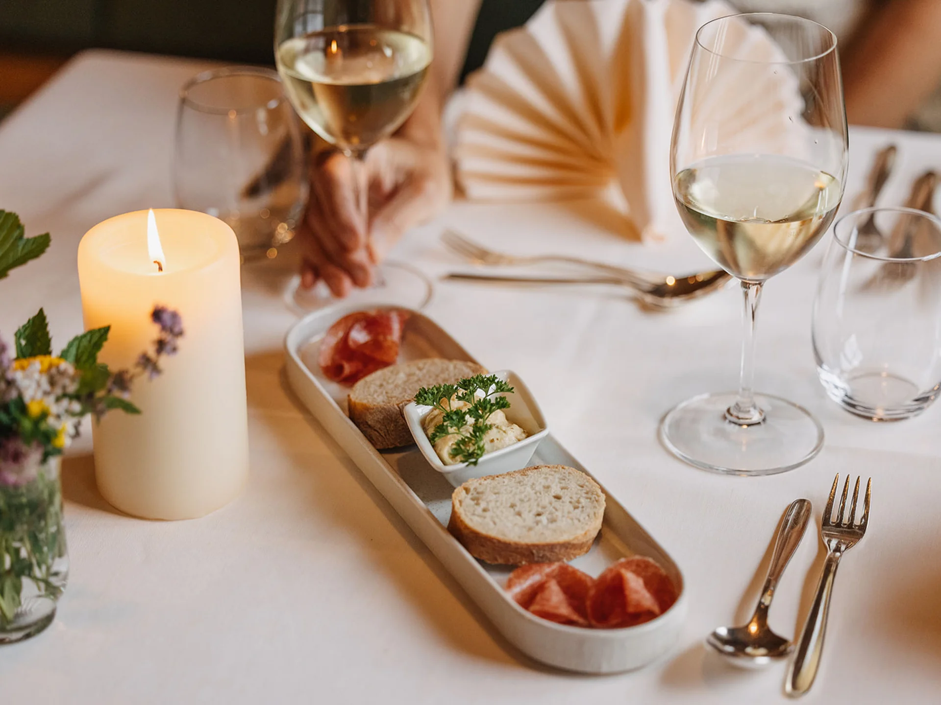 Candle, bread, spread, and wine on an elegantly set table