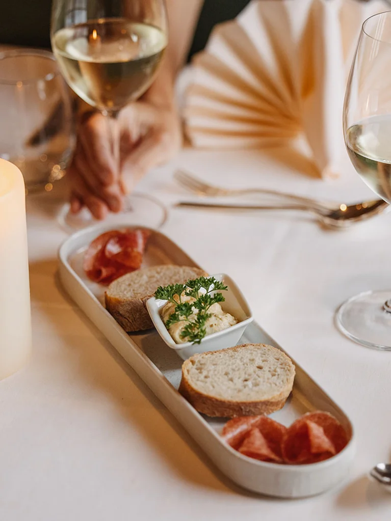 Kerze, Brot, Aufstrich und Wein auf elegant gedecktem Tisch