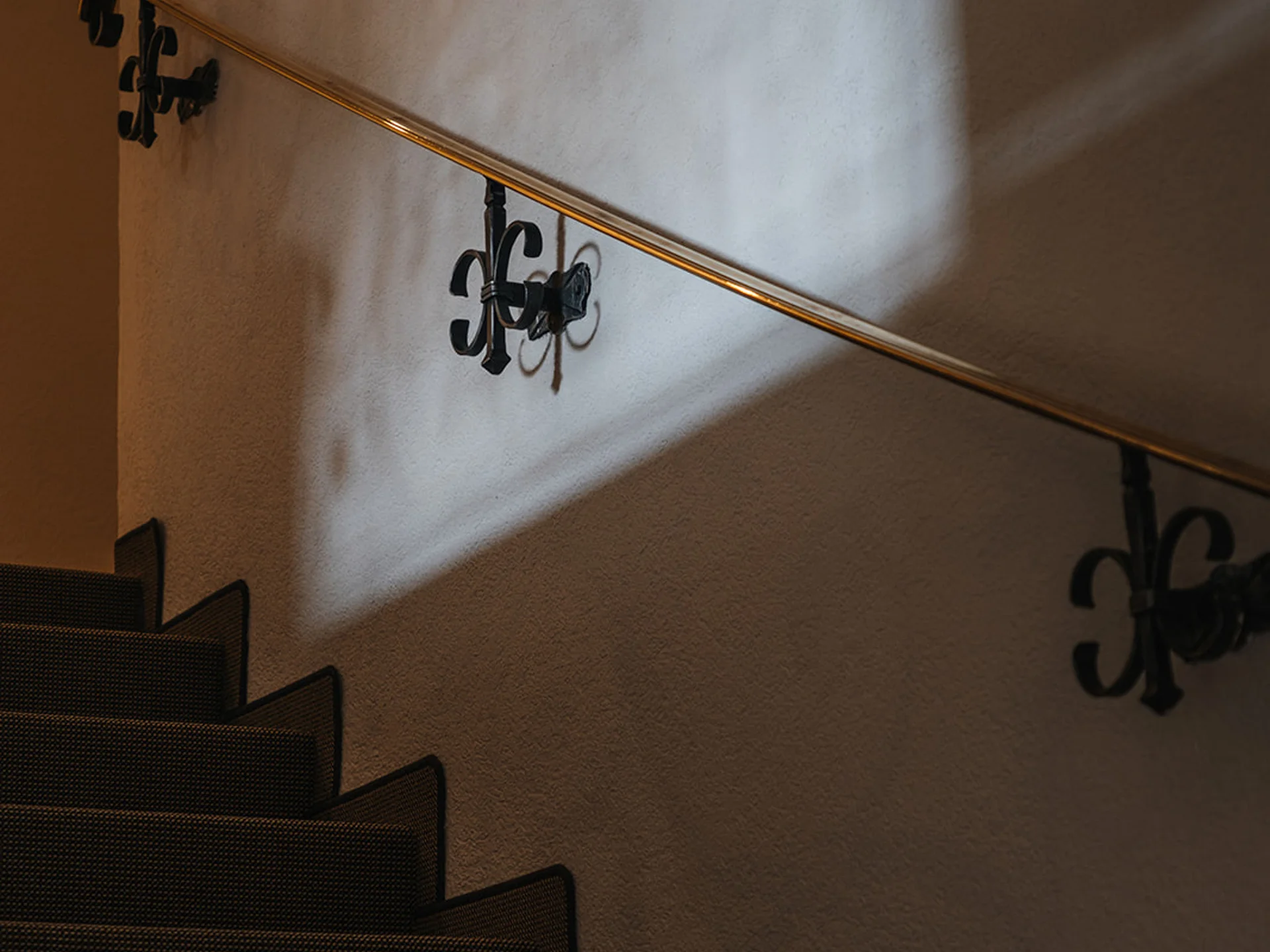 Dark carpeted staircase with illuminated handrail mounted on wall