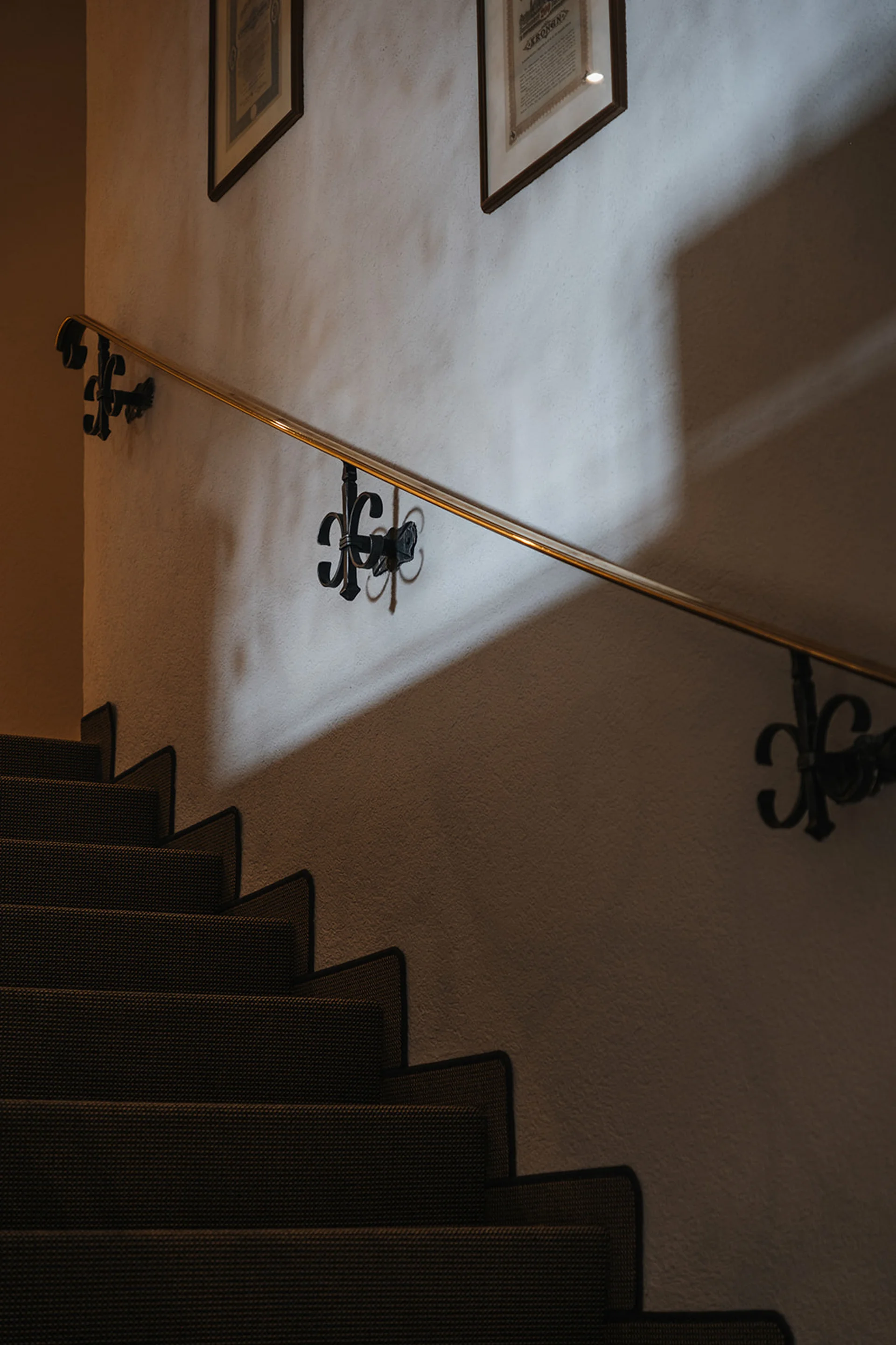 Dunkle Treppe mit Teppichläufer und beleuchtetem Handlauf an der Wand
