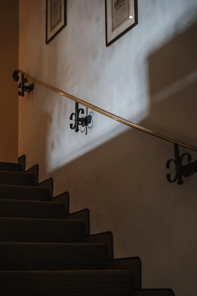 Dunkle Treppe mit Teppichläufer und beleuchtetem Handlauf an der Wand