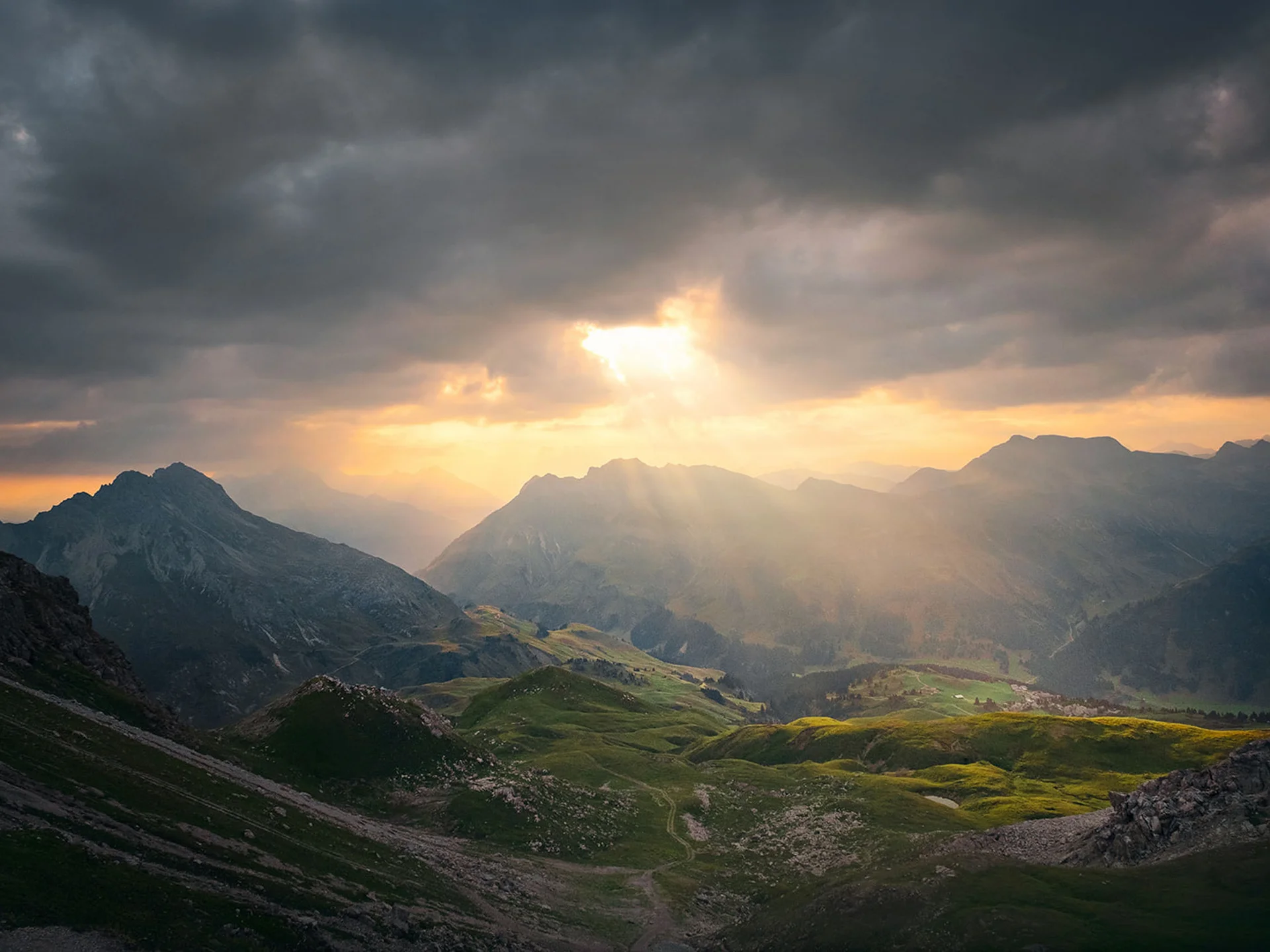 Sun rays piercing clouds over green mountains and valleys