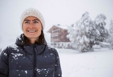 Frau vor verschneitem Haus Braunarl