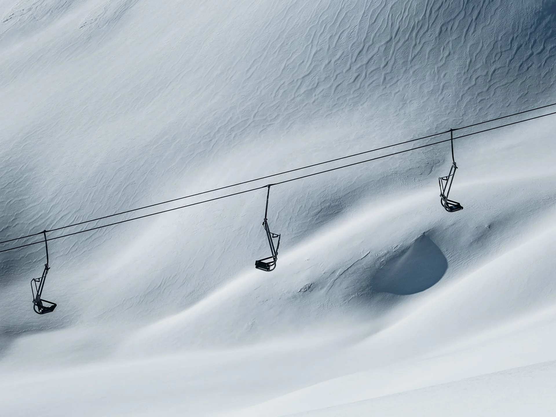 Empty ski lifts above snow-covered mountainous terrain