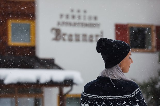 Frau mit Norwegerpulli vor Haus Braunarl im Winter