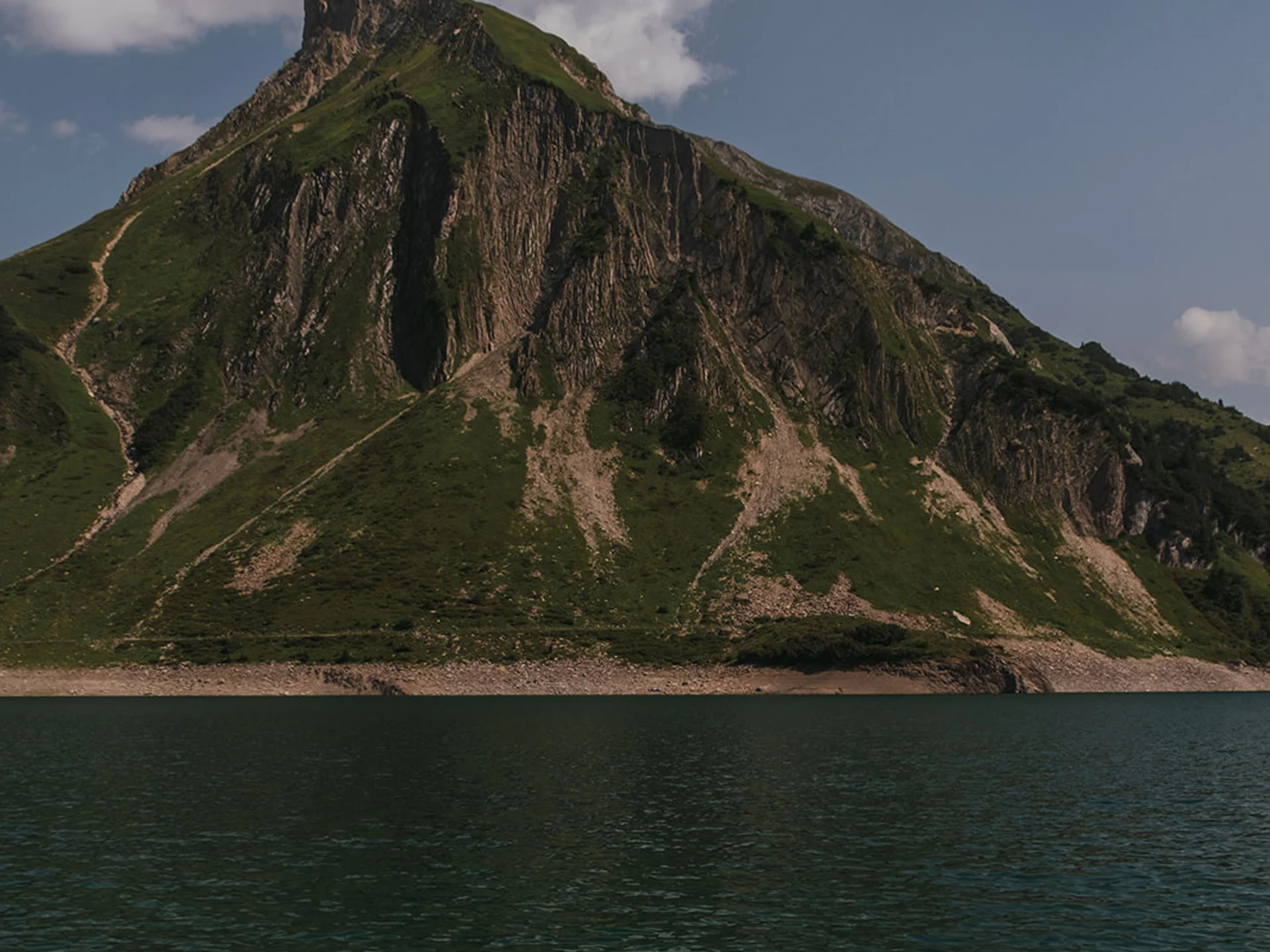 Woman relaxing floating on water with mountain backdrop under cloudy sky