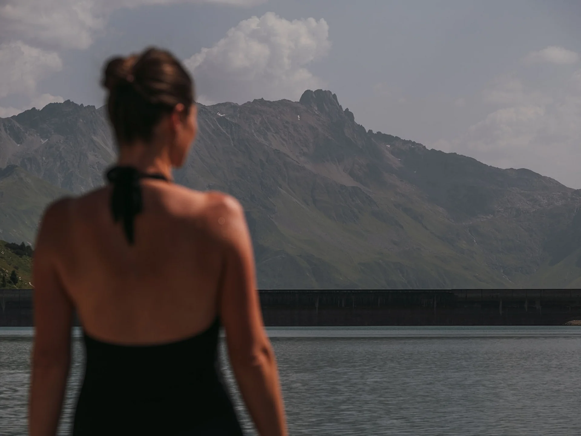 Woman looking at a lake with mountains in the background