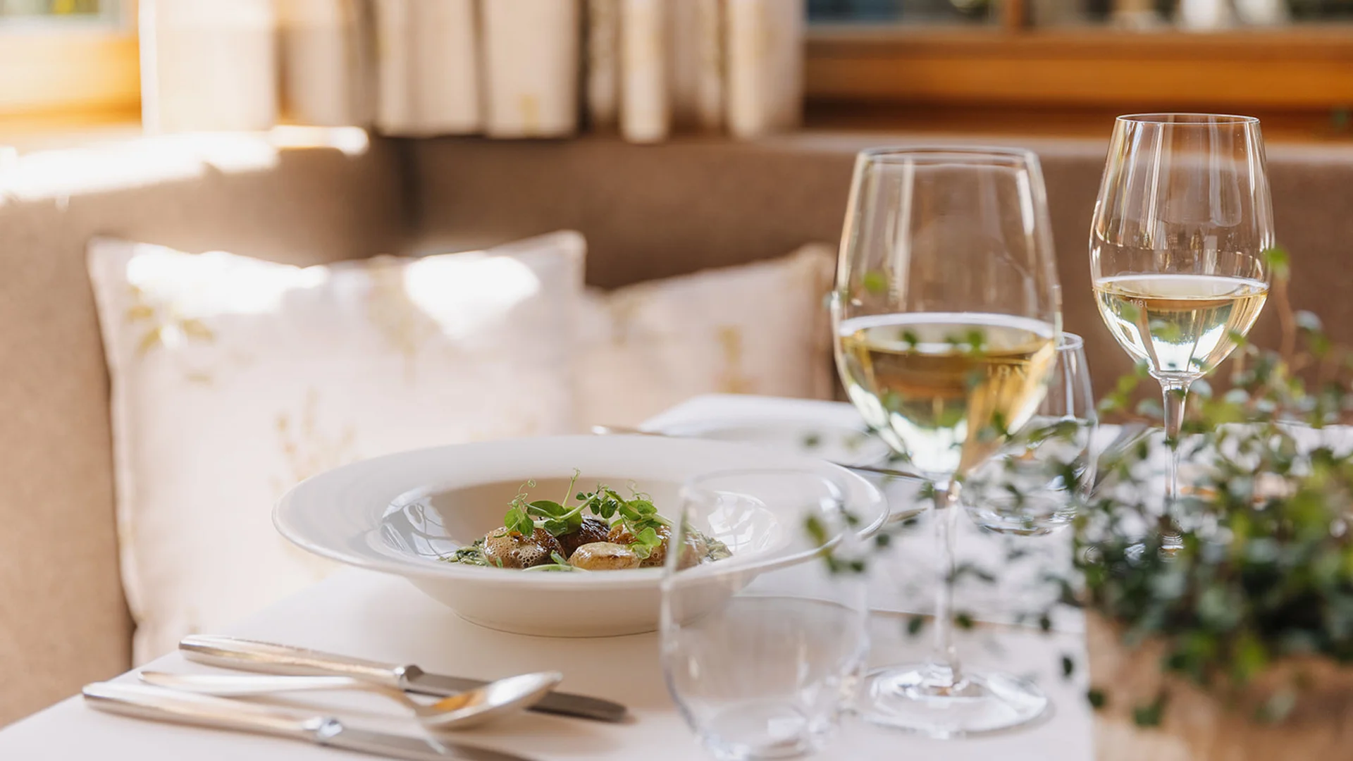 Fein gedeckter Tisch mit Gourmetgericht und zwei Gläsern Weißwein