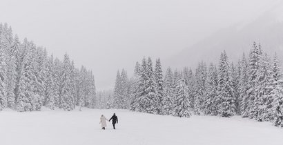 Ein Paar spaziert im Tiefschnee während es schneit